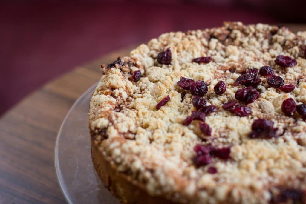 Pflaumenkuchen mit Streuseln – warmer Duft, wie ihn die AVA & MAY PLUM CAKE Duftkerze verströmt, inspiriert von herbstlicher Gemütlichkeit und süßen Backmomenten.